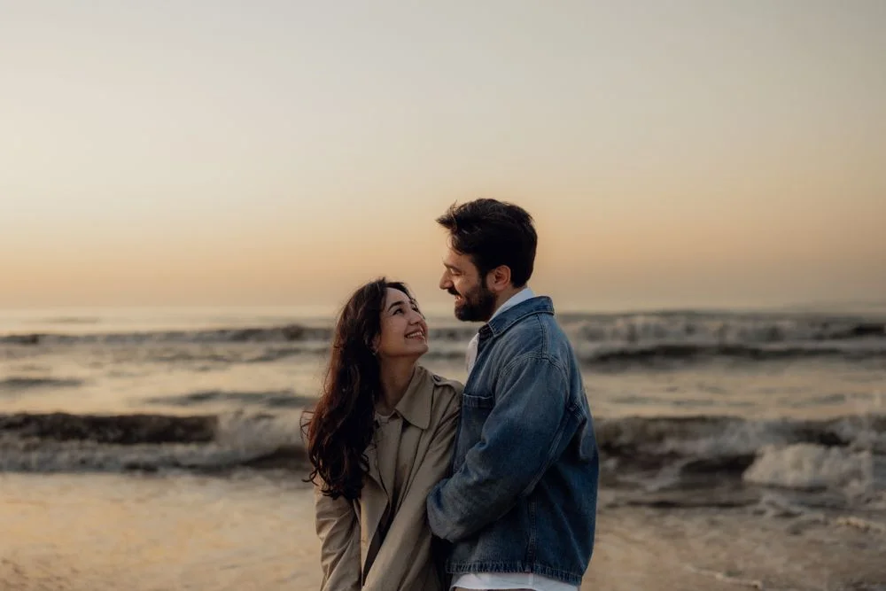 Una pareja se abraza durante un paseo por la playa al atardecer